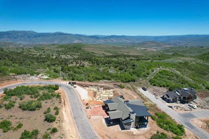 Expansive mountainous terrain with a single-family residence featuring a multi-gabled roofline and a flat roof section