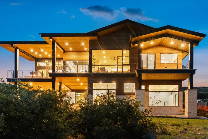 Multi-story contemporary exterior featuring extensive wood paneling, multiple covered balconies, large windows, and stone accents