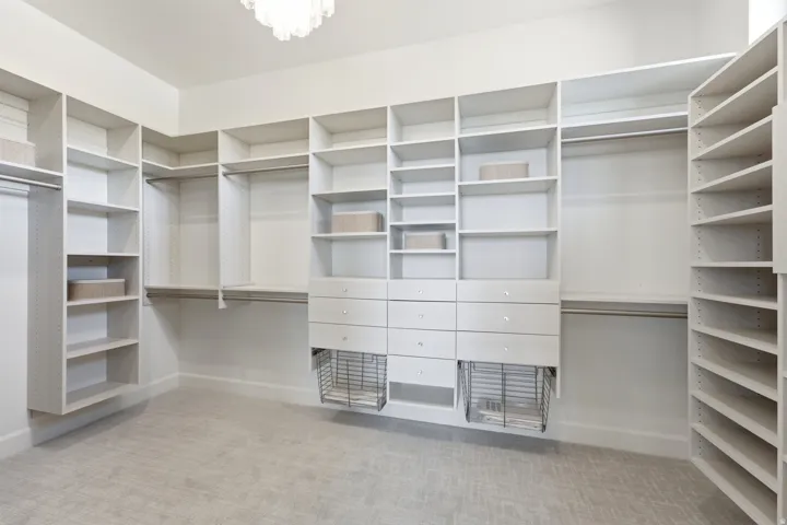 Custom closet system featuring extensive shelving, multiple hanging rods, built-in drawers, and integrated wire baskets