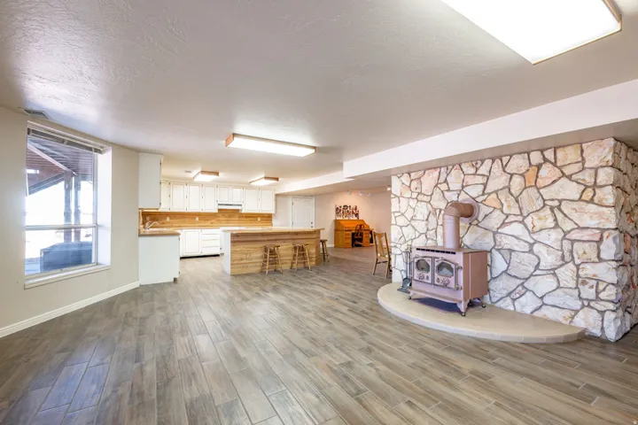 Kitchen with a wood stove, light countertops, wood finish floors, white cabinets, and a textured ceiling