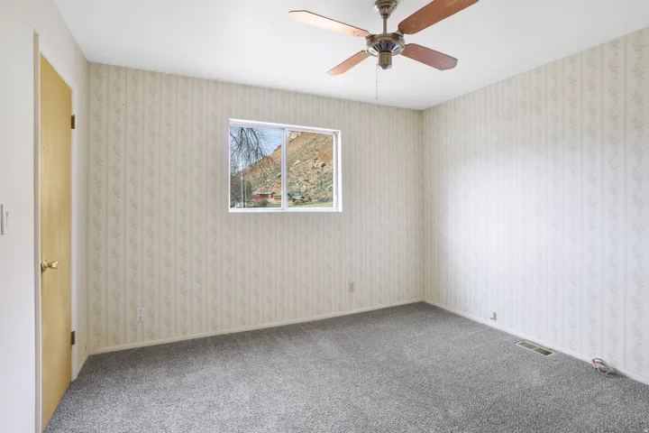 Empty room featuring ceiling fan and carpet flooring
