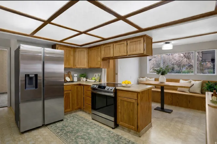 Kitchen featuring stainless steel appliances, light floors, wood finish cabinetry, light countertops, and breakfast area