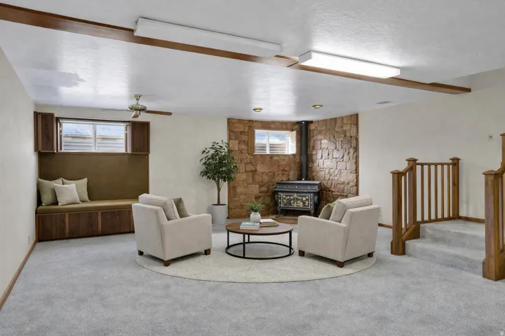 Carpeted living room featuring a wood stove and a ceiling fan