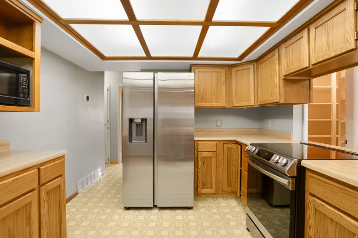 Kitchen with stainless steel appliances, light countertops, open shelves, and light floors