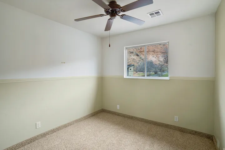 Carpeted empty room with ceiling fan and baseboards