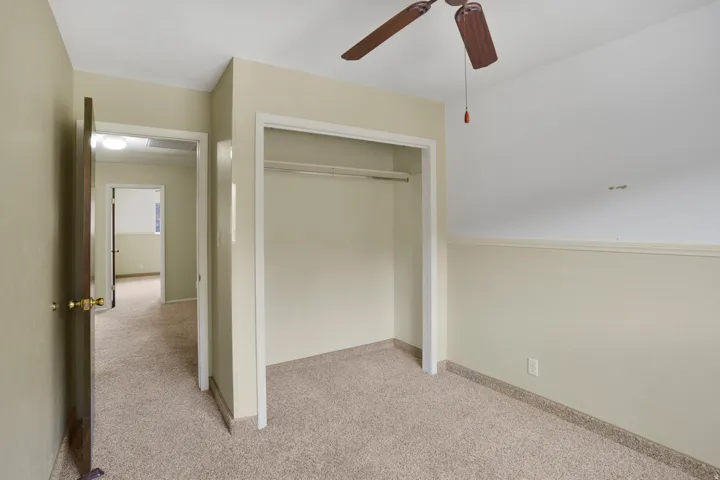 Unfurnished bedroom with light colored carpet, ceiling fan, and a closet
