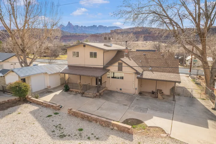 Rear view of property with a patio area, a mountain view, roof with shingles, a chimney, and stucco siding