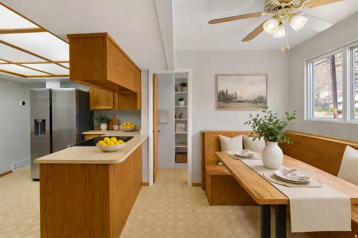 Kitchen with light countertops, wood finish cabinets, stainless steel fridge with ice dispenser, a peninsula, and light floors