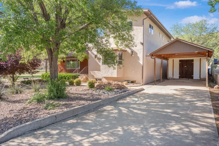 View of front facade with stucco siding, concrete driveway, and a carport