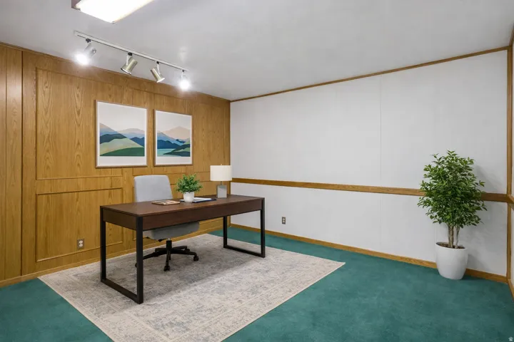 Office space with rail lighting, wooden walls, carpet, and a decorative wall