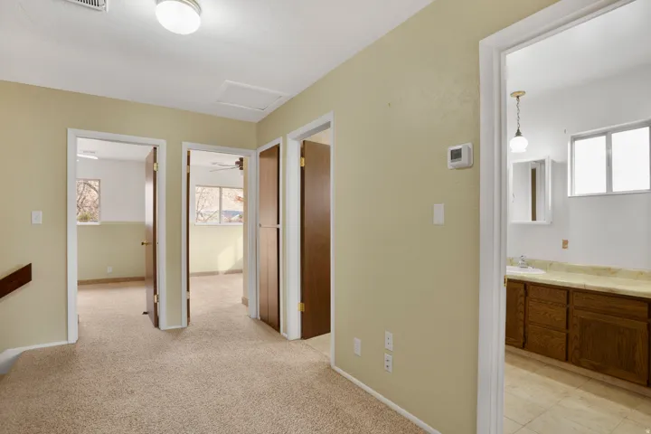 Corridor with attic access and light colored carpet