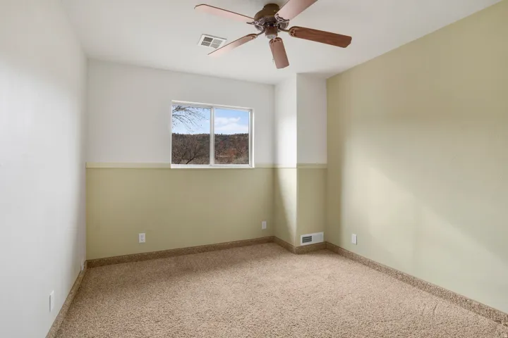 Carpeted spare room featuring a ceiling fan and baseboards