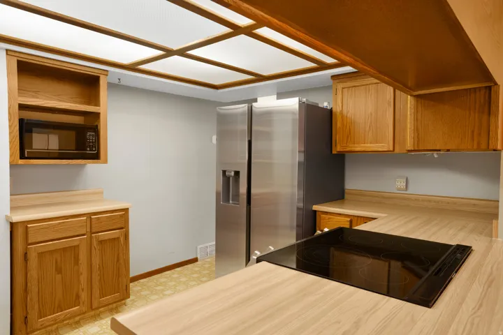 Kitchen featuring light countertops, brown cabinetry, stainless steel refrigerator with ice dispenser, and light flooring
