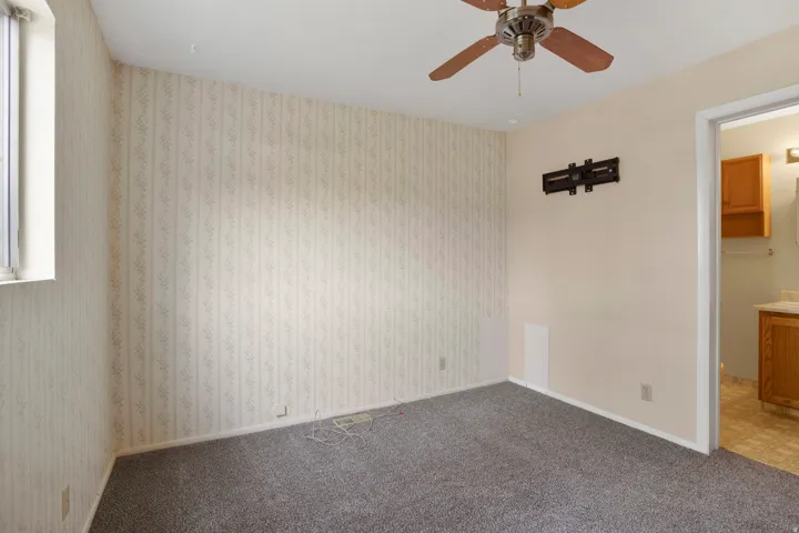 Empty room featuring a ceiling fan and carpet