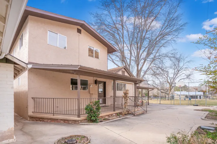 View of front of home with a porch, stucco siding, and concrete driveway
