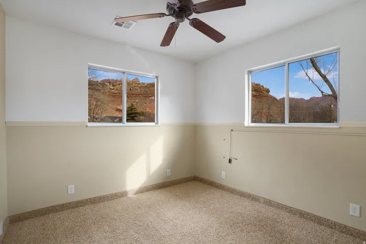 Carpeted spare room with a ceiling fan and baseboards