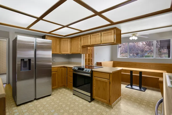 Kitchen with stainless steel appliances, light countertops, brown cabinetry, and a peninsula