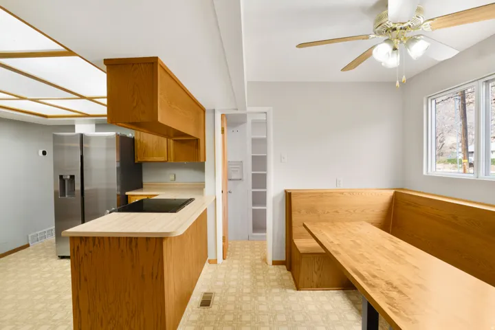 Kitchen featuring brown cabinetry, stainless steel refrigerator with ice dispenser, a peninsula, light floors, and black electric cooktop