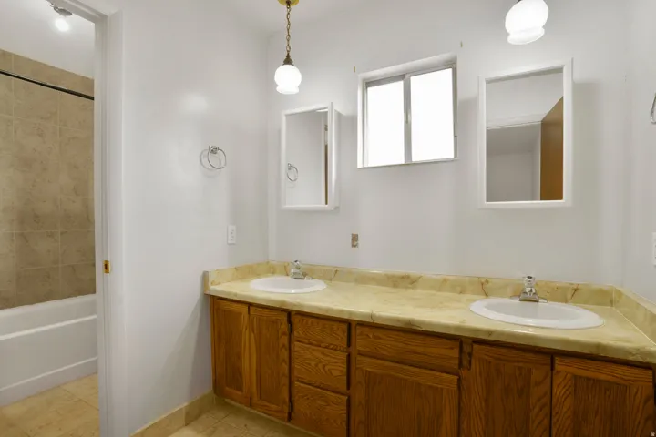 Bathroom featuring double vanity, light tile patterned floors, and shower / tub combination
