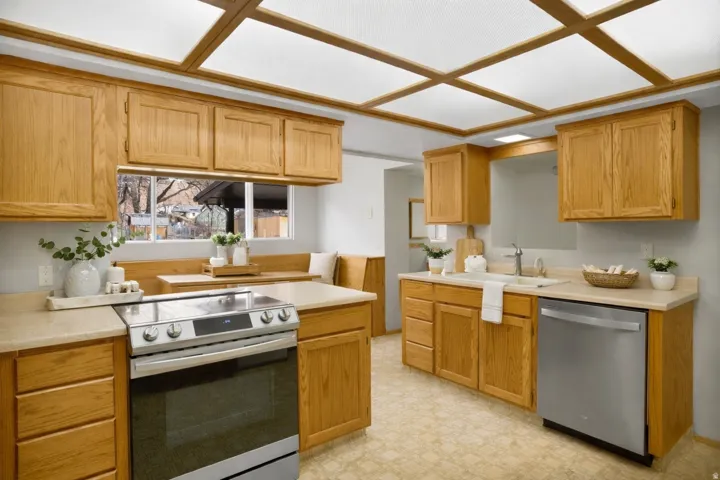 Kitchen featuring light countertops, stainless steel appliances, light flooring, and wood finish cabinetry