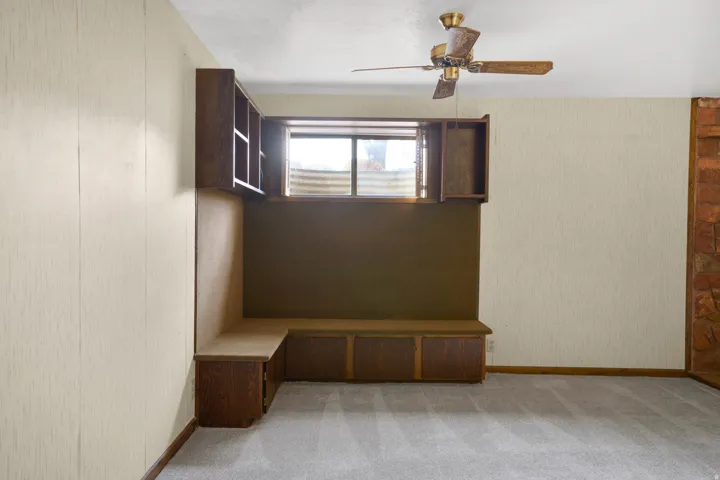 Spare room with wallpapered walls, a ceiling fan, and light carpet