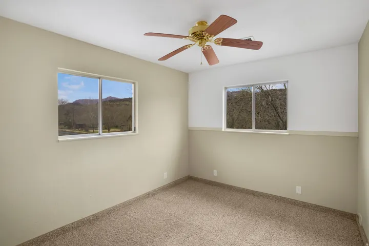 Unfurnished room featuring carpet floors, a ceiling fan, and a mountain view