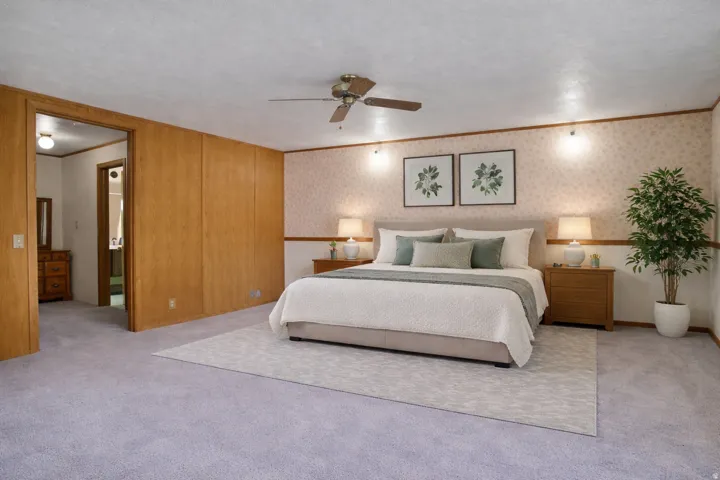 Bedroom with light colored carpet, ornamental molding, a ceiling fan, and wallpapered walls