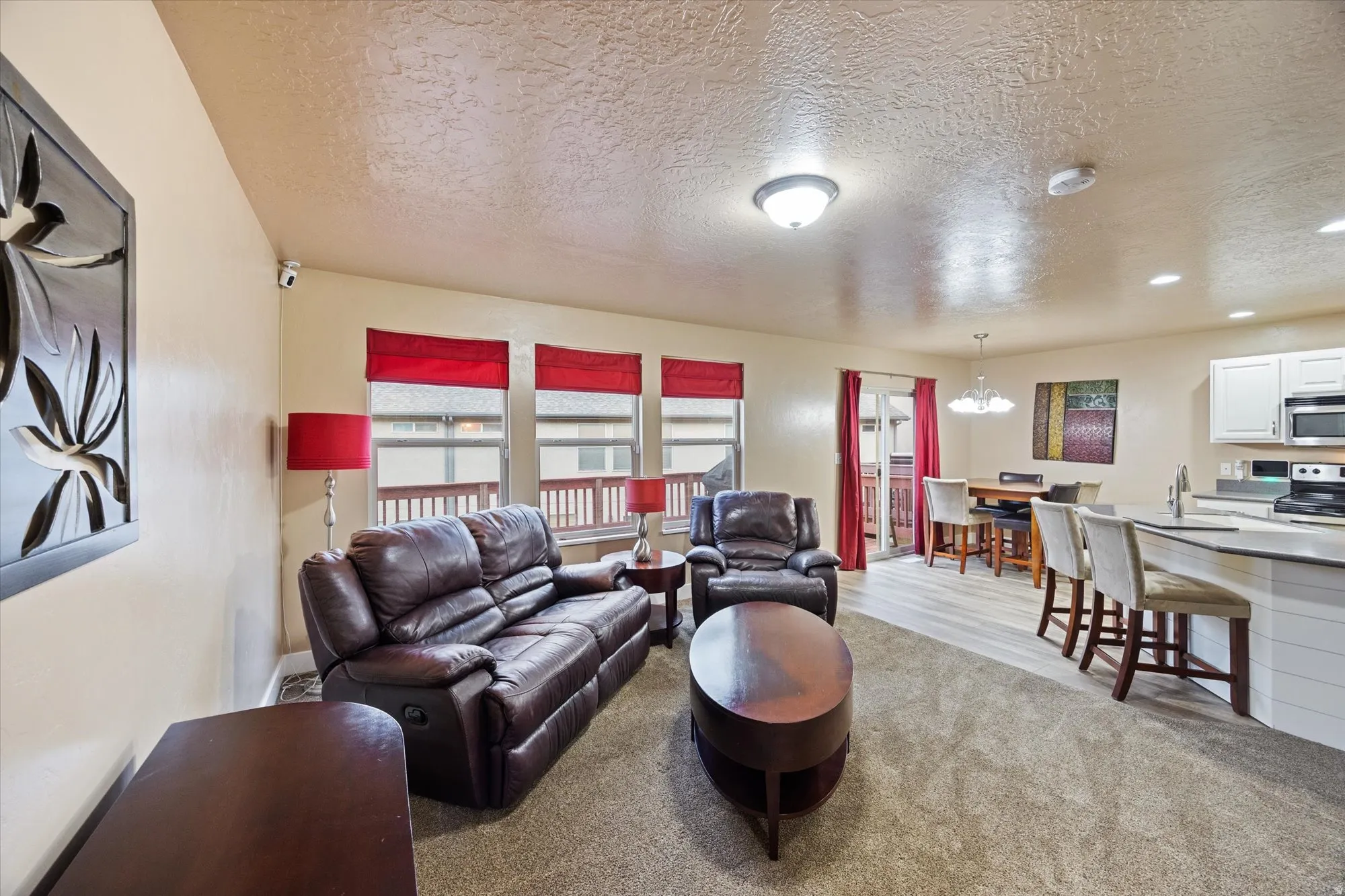 Living room with a textured ceiling, light carpet, a chandelier, and recessed lighting