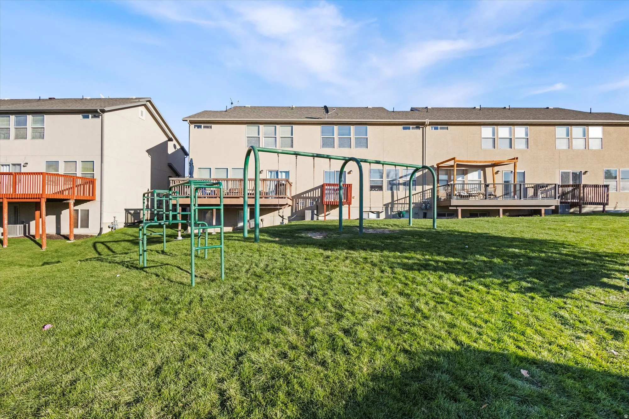 Rear view of house featuring a deck, a playground, and a lawn