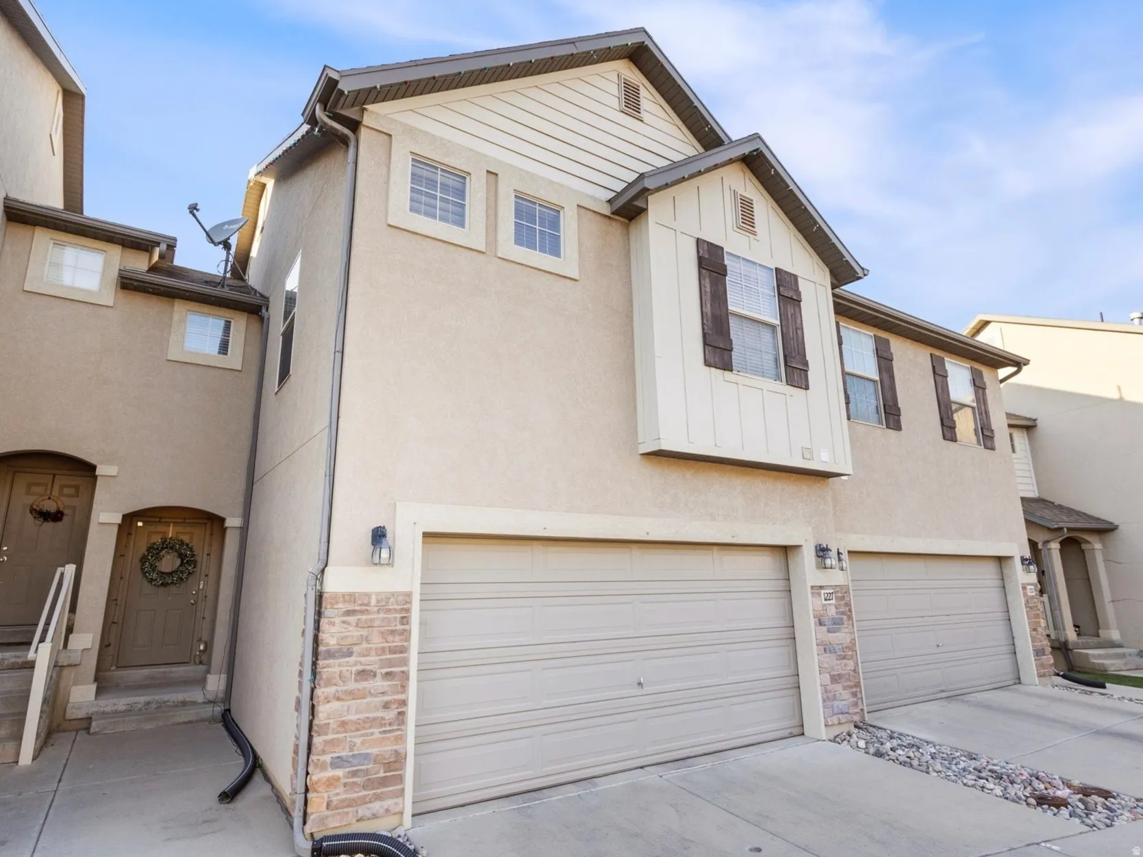 Traditional home featuring an attached garage, stucco siding, concrete driveway, and stone siding
