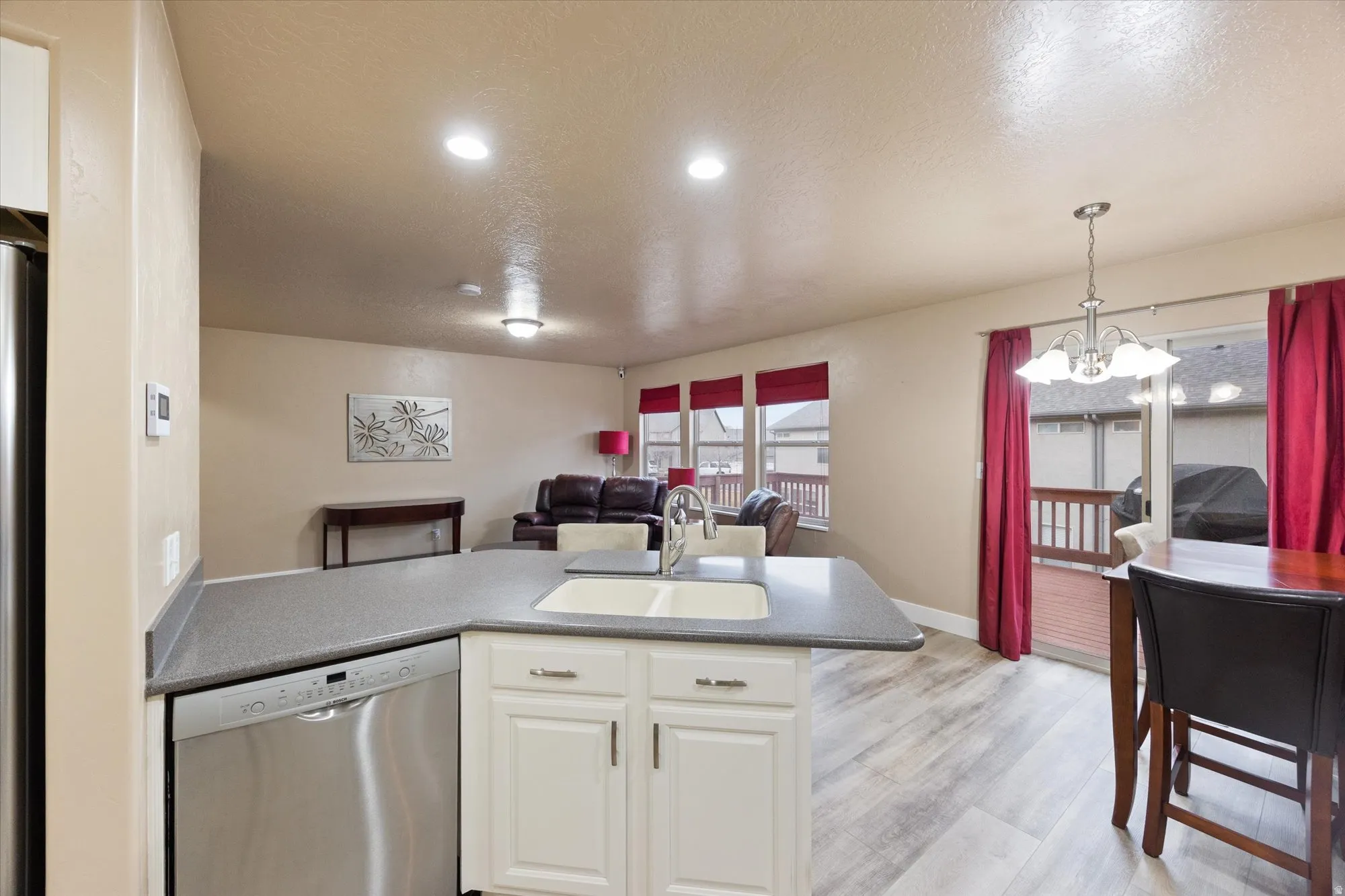 Kitchen with a peninsula, stainless steel appliances, open floor plan, pendant lighting, and a chandelier