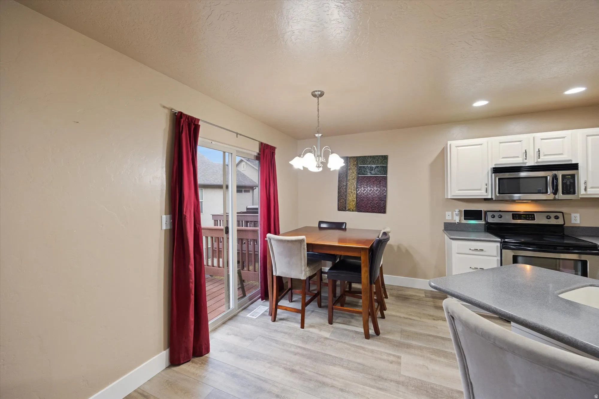 Dining area with a chandelier, a textured ceiling, light wood-style floors, and recessed lighting