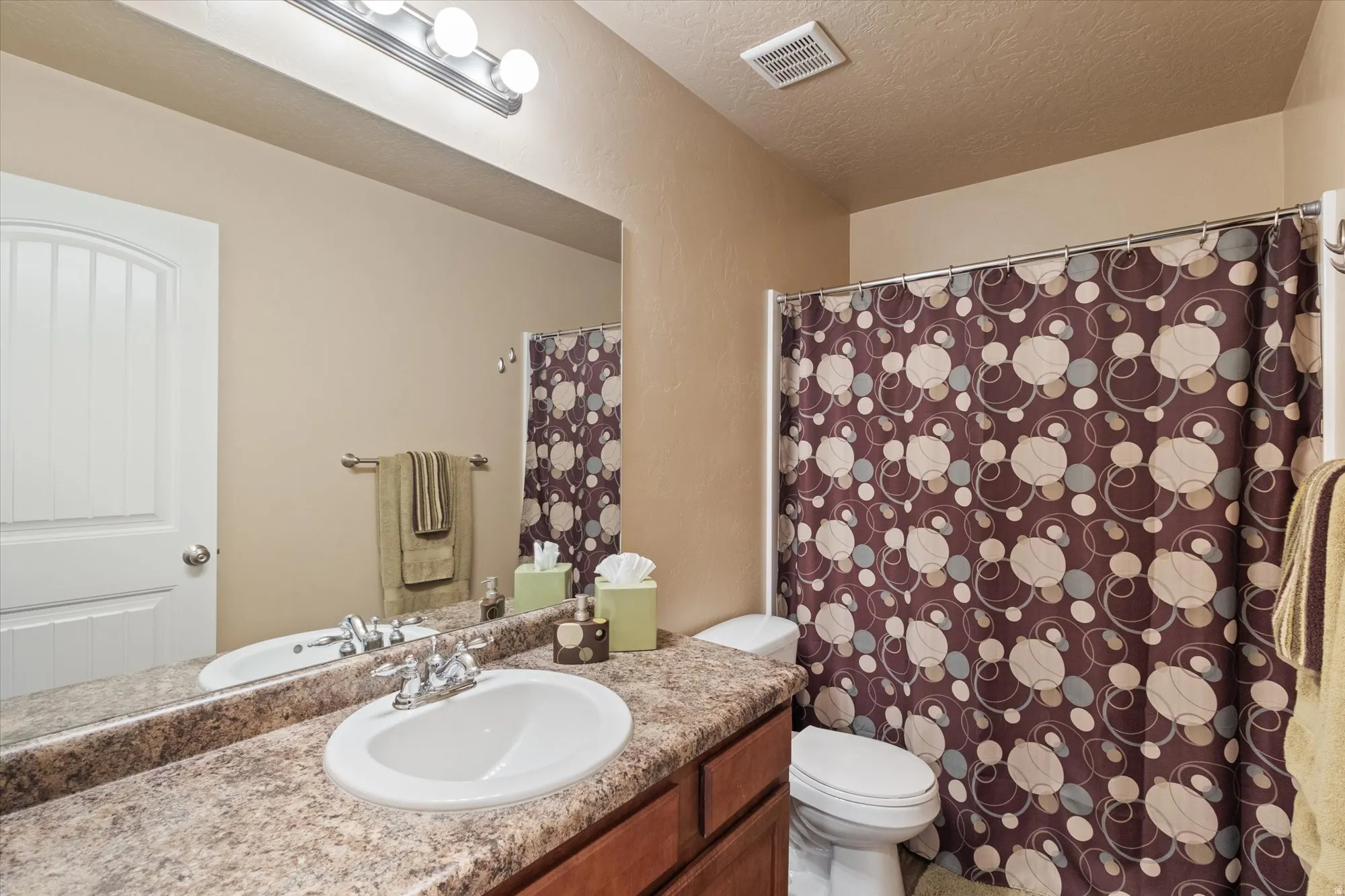 Bathroom with a shower with curtain, vanity, and a textured ceiling