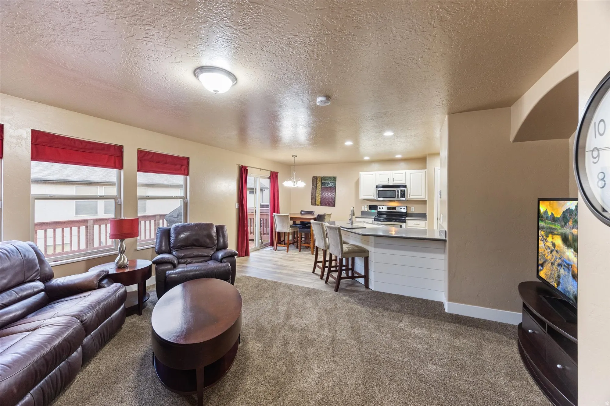 Living area with a textured ceiling, dark carpet, a chandelier, and recessed lighting
