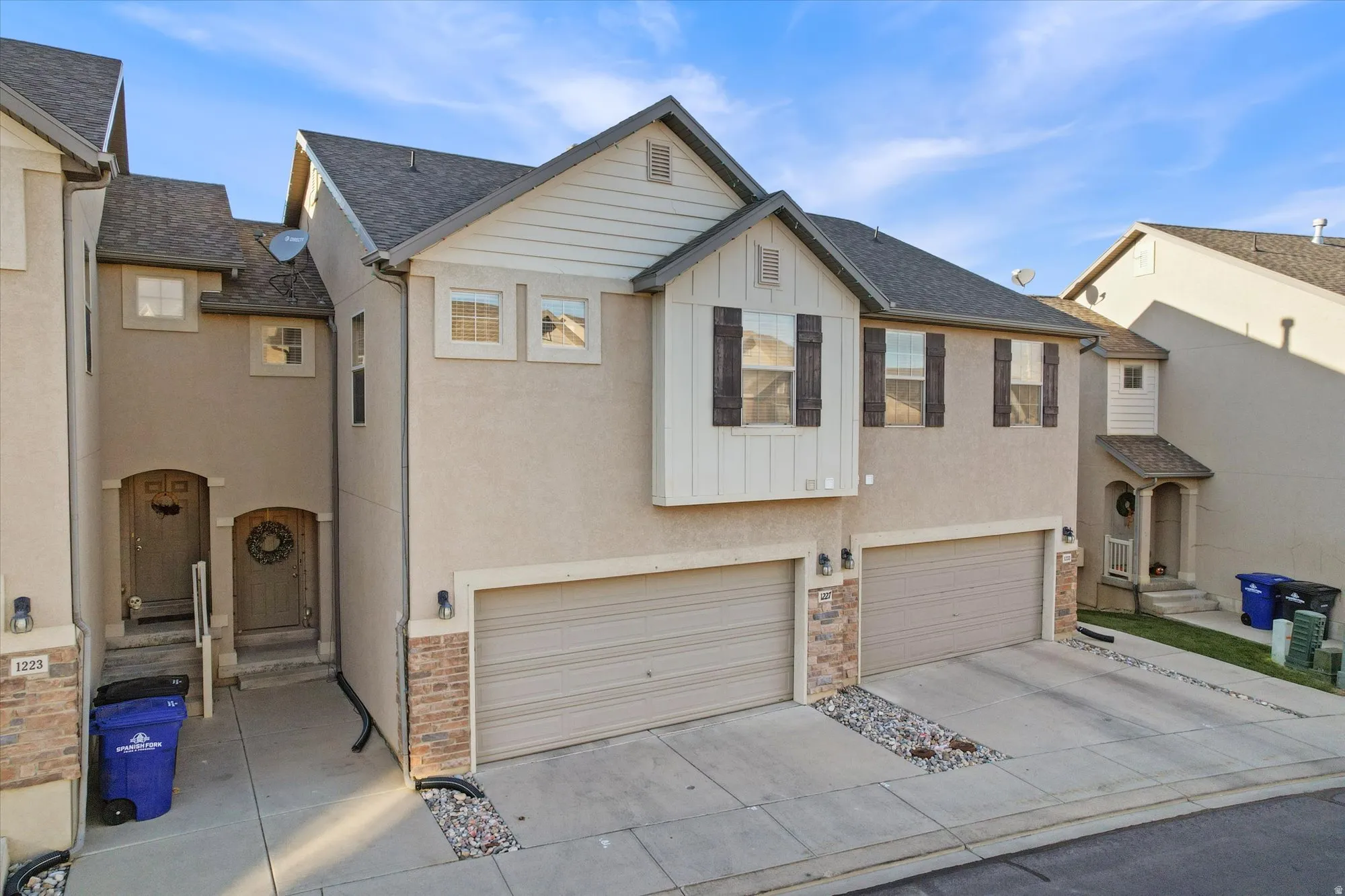 Traditional home featuring roof with shingles, concrete driveway, an attached garage, stucco siding, and board and batten siding