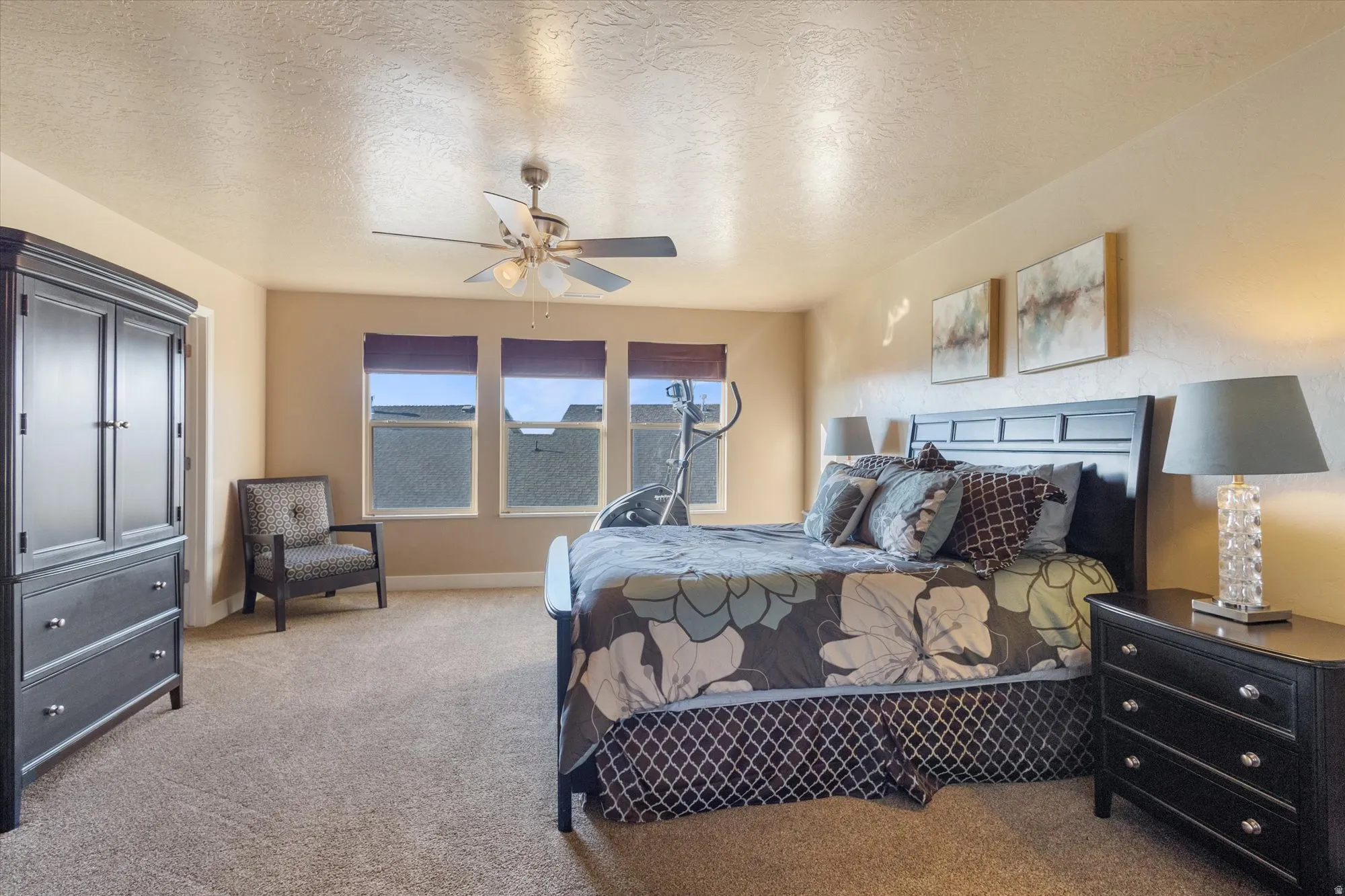 Carpeted bedroom featuring a textured ceiling and a ceiling fan