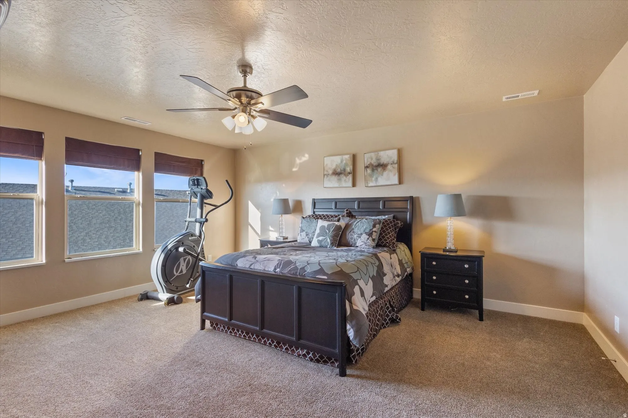 Bedroom featuring a textured ceiling, carpet floors, and ceiling fan