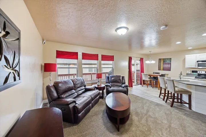 Living room with a textured ceiling, light carpet, a chandelier, and recessed lighting