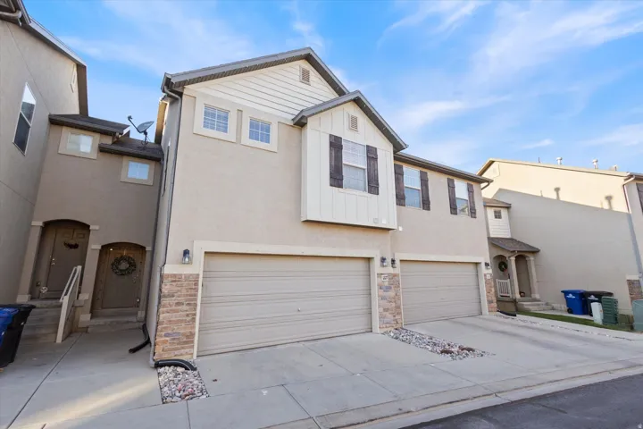 Traditional home featuring driveway, stone siding, a garage, and stucco siding