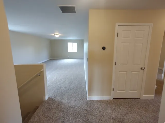 Hallway featuring carpet and an upstairs landing