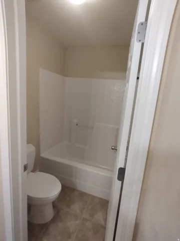 Bathroom featuring light tile patterned flooring and washtub / shower combination