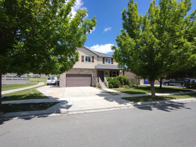 View of front facade featuring stone siding, concrete driveway, a garage, stucco siding, and covered porch