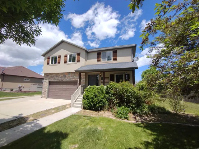 View of front of house featuring covered porch, stucco siding, stone siding, driveway, and a garage