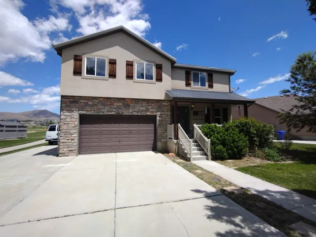 Traditional-style house featuring stucco siding, concrete driveway, a garage, stone siding, and a porch