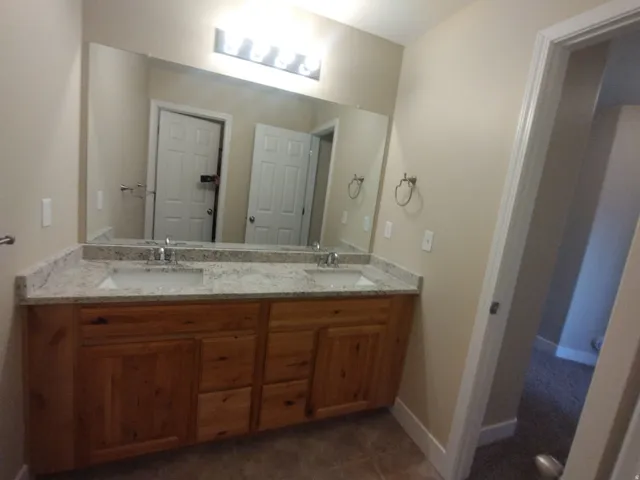 Bathroom with double vanity and dark tile patterned flooring