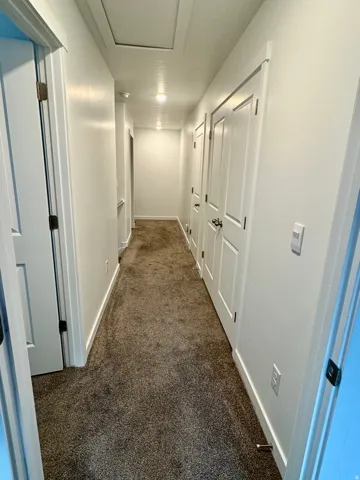 Corridor with dark colored carpet and baseboards