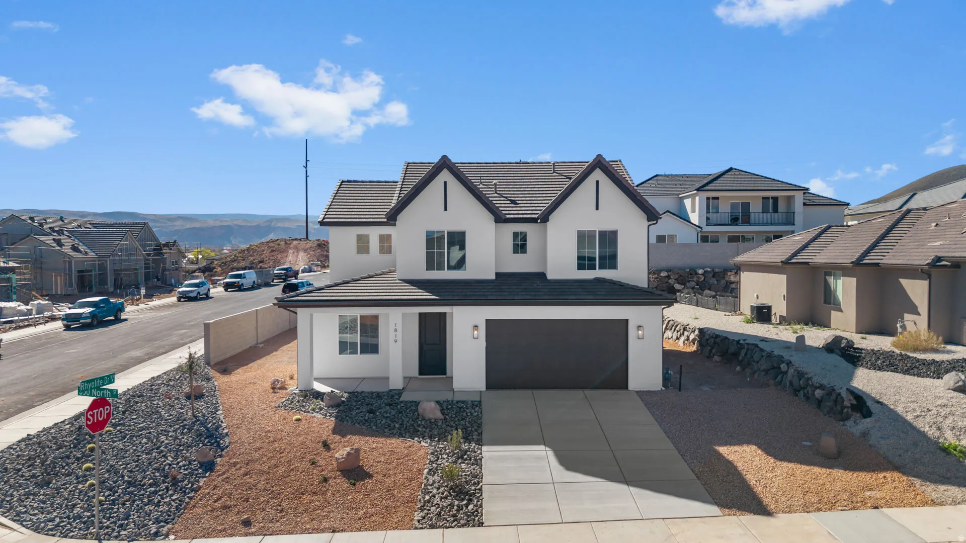 View of front of home with a garage, a residential view, stucco siding, driveway, and a tile roof