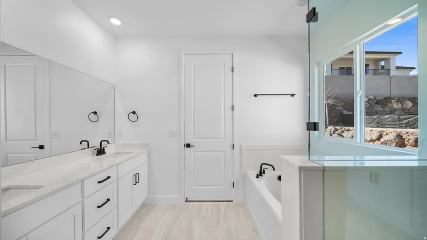 Full bathroom with double vanity, a bath, and recessed lighting