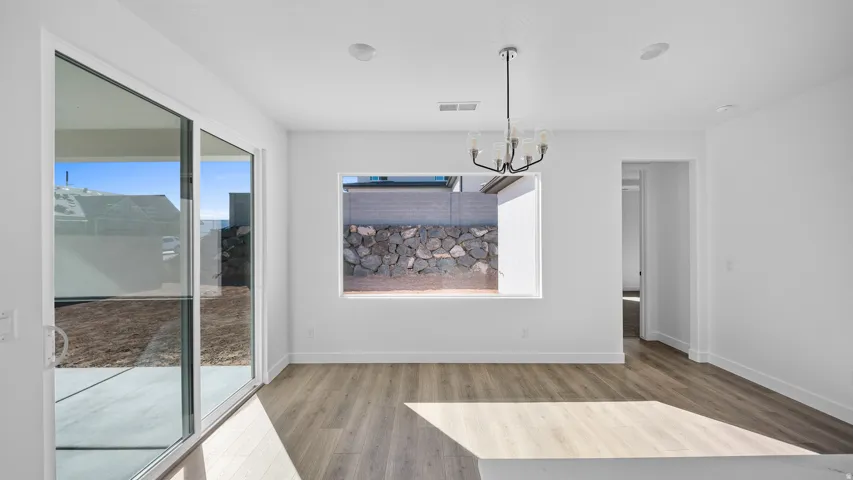 Unfurnished dining area featuring light wood-type flooring and hanging lights