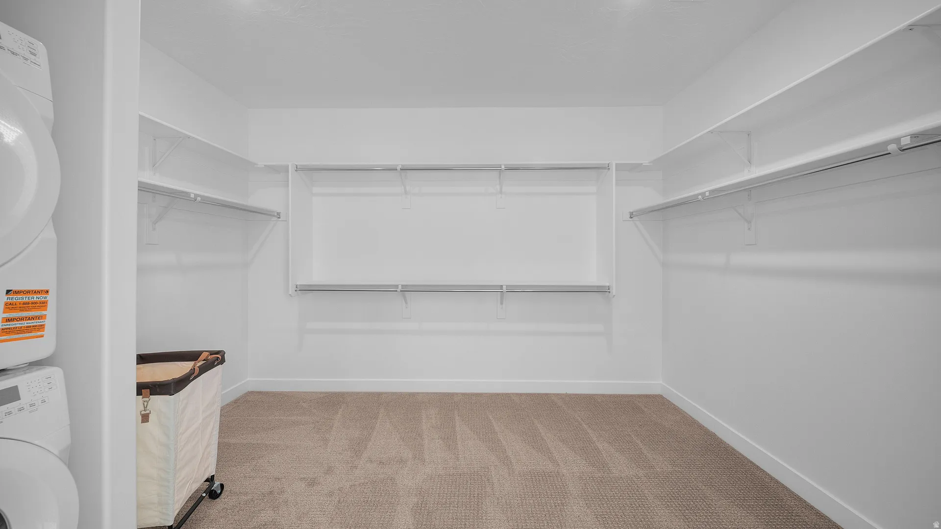 Walk in closet featuring light colored carpet and stacked washer / dryer